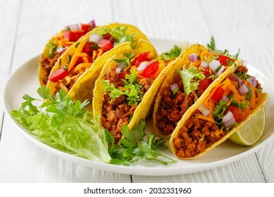 Ground Beef Tacos With Shredded Cheddar Cheese, Fresh Lettuce, Tomato, Onion On A White Plate With Lime Wedges, Horizontal View From Above, Mexican Cuisine