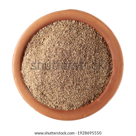 Ground carob powder (Ceratonia siliqua) in clay pot isolated on white background, top view