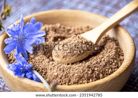 Ground chicory root on a wooden spoon and chicory flowers on a rustic wooden background. Alternative medicine. Healthy drinks. chicory drink Foto stock © 