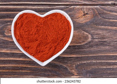 Ground Chili Pepper In A Bowl In The Form Of Heart On A Wooden Background