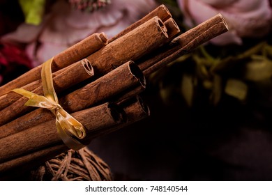 Ground cinnamon, cinnamon sticks, connected with a tray with a bow on a color background in a rustic style. Macro photo with selective focus. Close up food concept. Vintage toning. Retro style. - Shutterstock ID 748140544