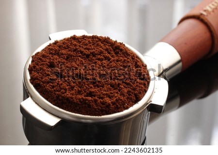 Ground coffee beans in portafilter on glass countertop, Espresso machine barista portafilter preparation. Selective focus