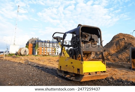Ground Compactor Plate on compact soil. Plate Compactor for Ground compact on construction site. Vibratory plate on compacting beating sand at sidewalk. Pressing gravel for laying paving slabs