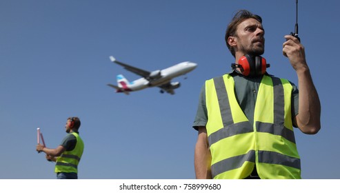 Ground Crew Dialogue With  Air Traffic Control Tower Using A Walkie Talkie, Airport Team Activity, Airplane Flying Over Aircrew Controllers, Aircraft Passing Overhead