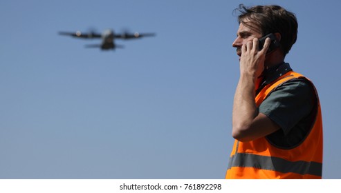 Ground Crew Service Man Talking On Mobile Phone With Air Traffic Control While Airplane Flying, Airport Staff Activity