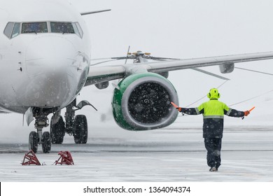 Ground Crew in the signal vest. Aviation Marshall / Supervisor meets passenger airplane at the airport. Aircraft is taxiing to the parking place. 