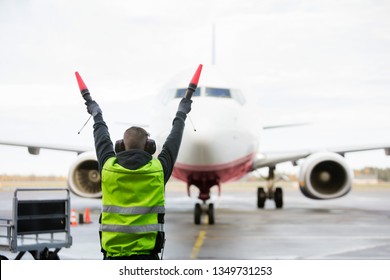 Ground Crew Signaling To Airplane On Runway