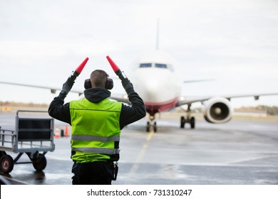 Ground Crew Signaling To Airplane On Wet Runway