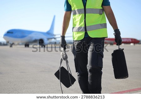 Ground crew worker performing essential ground handling services near airplanes on a sunny day