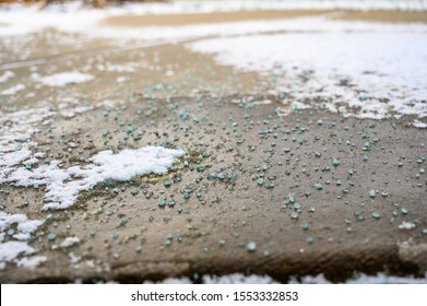 Ground Level Closeup View Of Rock Salt Ice-melt  On Concrete With Snow