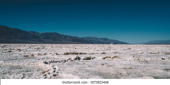 Ground Level Of Picturesque Desert With Snowy Rough Surface Located Near Cold Hills Covered With Hoarfrost During Sunny Day Of Severe Winter