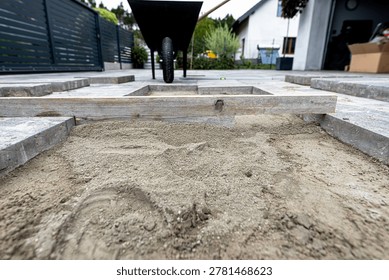 Ground leveling process for driveway construction using a wooden bar and sand