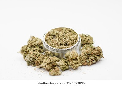 Ground marijuana in aluminum grinder, with buds, white background.