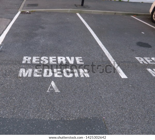 \
Ground marking in french\
(reserve medecin) on asphalt in a car park: reserved for the\
doctor.
