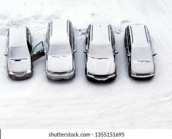 Ground parking cars after snowfall in winter, view from above, top or aerial view. Automobiles covered with snow, the traces of wheels and legs. Copy space for text box and design. White background