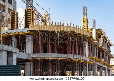 Ground parking construction. Erection of architectural structures. Unfinished house with concrete frame. Construction site without builders. Use of temporary metal supports in construction