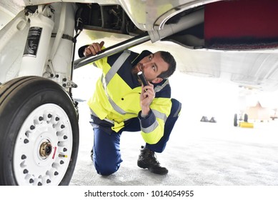 Ground personnel at the airport check the hydraulic system of the landing gear of the aircraft  - Powered by Shutterstock