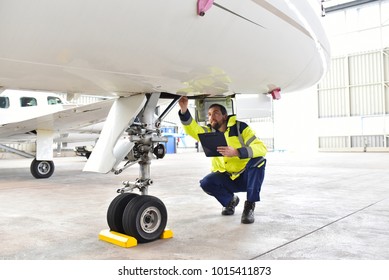 Ground personnel at the airport check the hydraulic system of the landing gear of the aircraft  - Shutterstock ID 1015411873