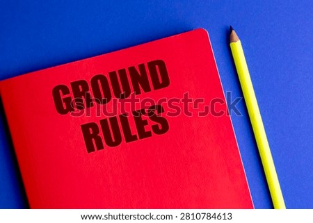 Ground rules text on red notebook with yellow pencil on blue background representing guidelines regulations compliance. 