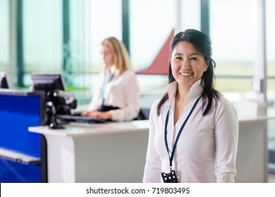 Ground Staff Smiling While Colleague Working At Airport Receptio