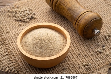ground white pepper in wooden bowl on wood table