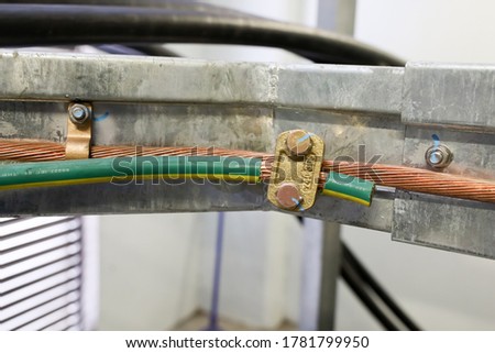 The grounding yellow/green pvc insulated connection with bare copper from cable tray for safety ground of electrical panel