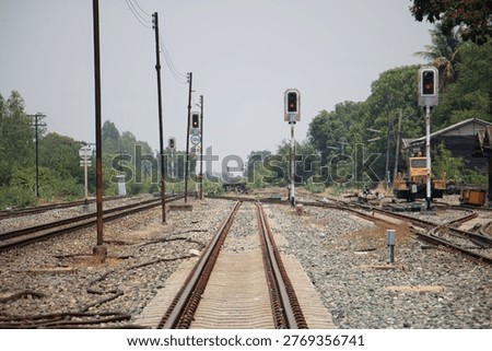 Ground-level view of intersecting railway tracks with red signal lights in a countryside setting. Infrastructure, transportation network, and industrial rail system concept.