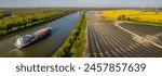 Ground-mounted solar photovoltaic panels near canal, where ships gracefully navigates waterway. Photovoltaic and wind park with freight ships on Kiel Canal.Container ship on Kiel Canal with solar park