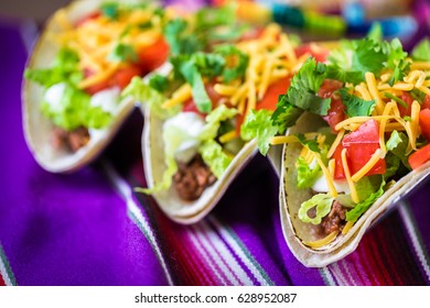 Groung Beef Tacos With Romaine Lettuce, Diced Tomatoes, And Shredded Cheddar Cheese.