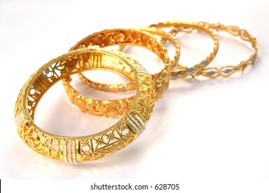 A group of 22k gold bracelets, showing details of the workmanship. The one at the front is inlaid with small Gulf pearls. The style is Arabian or Indian/Eastern.