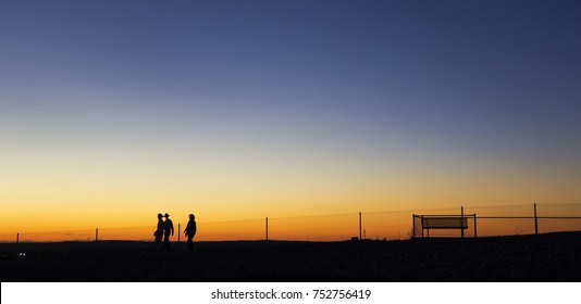 Group Of 3 People Walking At Sunset In Outback Australia. Silhouette Panorama. Broken Hill, New South Wales, Australia. Copy Space For Banner Text.