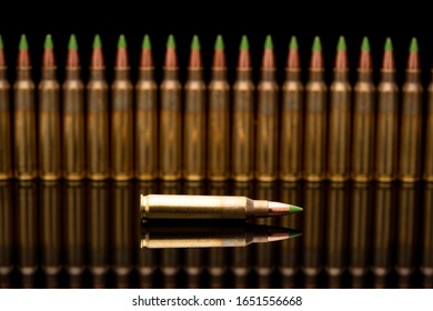 A group of 5.56 calibar, green tip bullets ordered into the line on black background