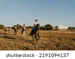 group of 6 horsemen riding through a meadow at sunset