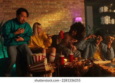 A group of 90s retro styled friends are at home enjoying eating takeout food on a sofa. - Powered by Shutterstock