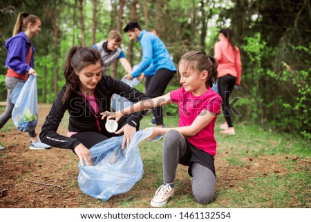 Group of active people picking up litter in nature, a plogging concept.