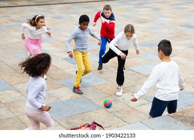 Group of active schoolchildren playing football together on the street - Powered by Shutterstock