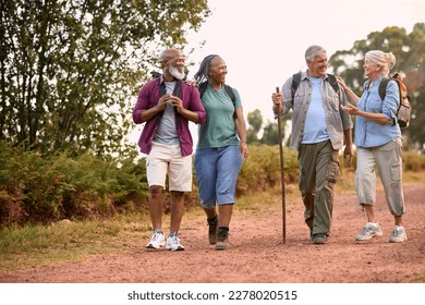 Group Of Active Senior Friends Enjoying Hiking Through Countryside Walking Along Track Together - Powered by Shutterstock