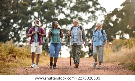 Group Of Active Senior Friends Enjoying Hiking Through Countryside Walking Along Track Together