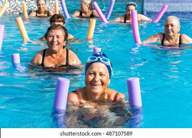 Group of active senior women doing aqua gym in outdoor swimming pool.