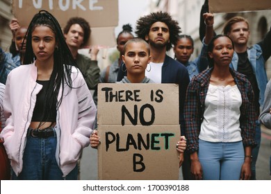 Group of activists with banners protesting over pollution and global warming. Male and female rebellions doing a silent protest to save planet earth. Woman holding a banner of 'There is no Planet B'. - Shutterstock ID 1700390188