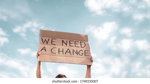 Group Of Activists With Banners Protesting Over Pollution And Global Warming. Male And Female Rebellions Doing A Silent Protest To Save A Planet Earth. Woman Holding A Banner Of 'We Need A Change'. 