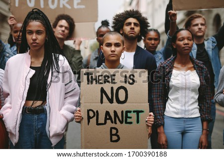 Group of activists with banners protesting over pollution and global warming. Male and female rebellions doing a silent protest to save planet earth. Woman holding a banner of 'There is no Planet B'.