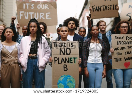 Group of activists with banners protesting to save earth. Men and women rebellions doing a silent protest over global warming and pollution.