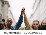 Group of activists with holding hands protesting in the city. Rebellions doing demonstration on the street holding hands.