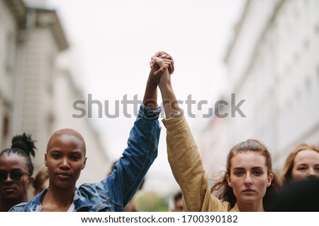 Group of activists with holding hands protesting in the city. Rebellions doing demonstration on the street holding hands.