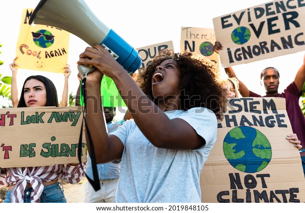 Group of activists protesting for climate\
change - Multiracial people fighting on road holding banners on\
environments disasters - Global warming\
concept
