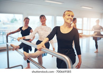 Group Of Adult Ballerinas Exercising And Doing Gymnastics At Handrail In The Ballet Class.