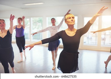 Group Of Adult Ballerinas Standing With Hands Up In Class For Ballet Performing A Dance.