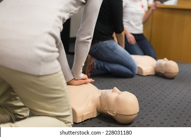 A group of adult education students practitcing CPR chest compressioon on a dummy. 