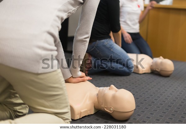 A group of adult education\
students practitcing CPR chest compressioon on a dummy.\
